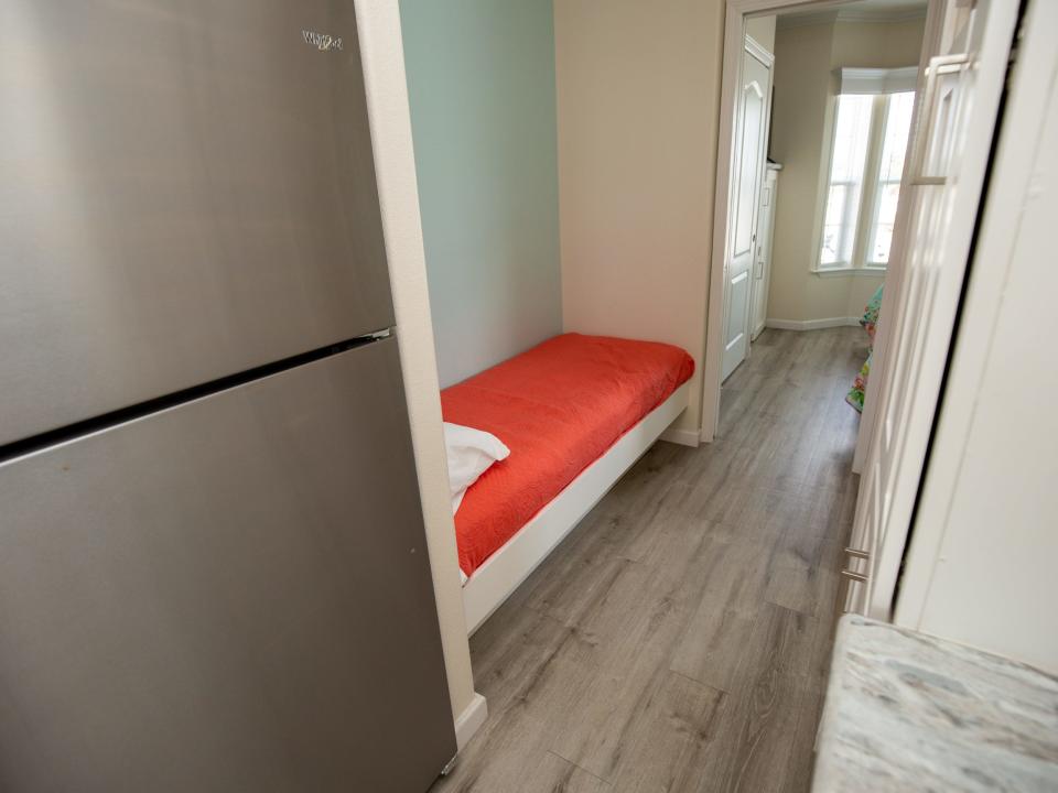 A fridge next to a bed.