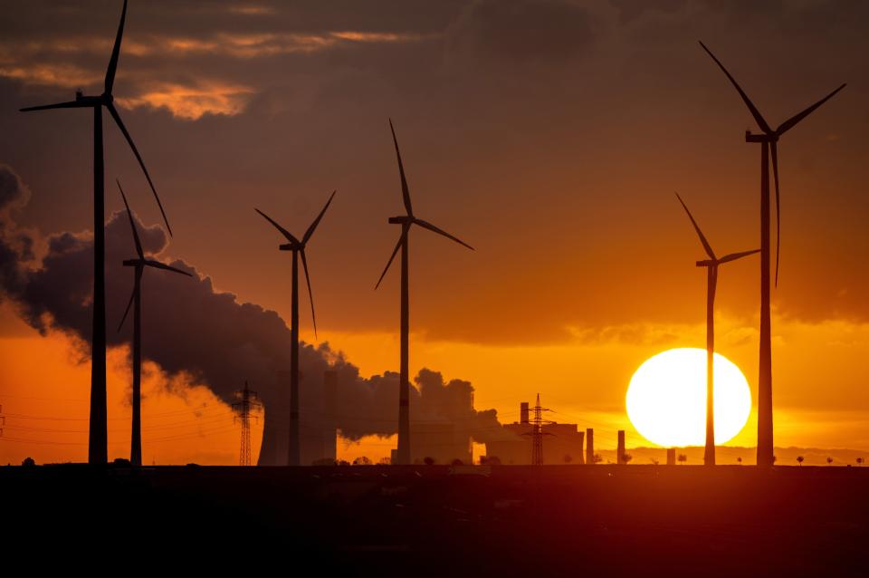 FILE - Steam rises from the coal-fired power plant near wind turbines in Niederaussem, Germany, as the sun rises on Nov. 2, 2022. Germany is shutting down its last three nuclear power plants on Saturday, April 15, 2023, as part of an energy transition agreed by successive governments. Critics have warned that without nuclear power, Germany will have to rely on dirty coal and gas plants for energy during periods of overcast but calm weather. (AP Photo/Michael Probst, File)