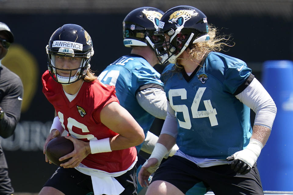 Jacksonville Jaguars quarterback Trevor Lawrence, left, runs a drill as offensive linemen Walker Little, center, and Austen Pleasants (64) block during an NFL football rookie minicamp, Saturday, May 15, 2021, in Jacksonville, Fla. (AP Photo/John Raoux)