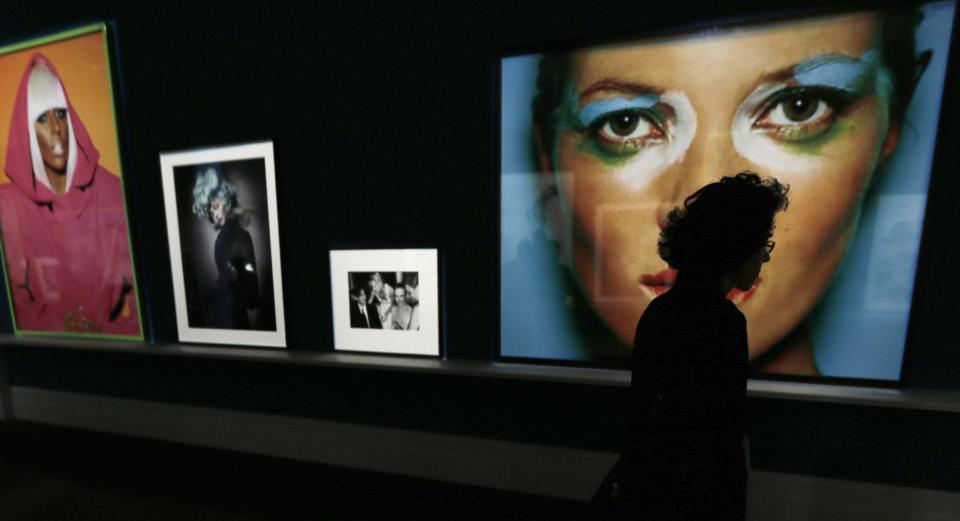 A woman walks past a large portrait of Kate Moss, right, by photographer Mario Testino during the preview of his shows "In Your Face" and "British Royal Portraits" at the Museum of Fine Arts in Boston, Wednesday, Oct. 17, 2012. (AP Photo/Charles Krupa)