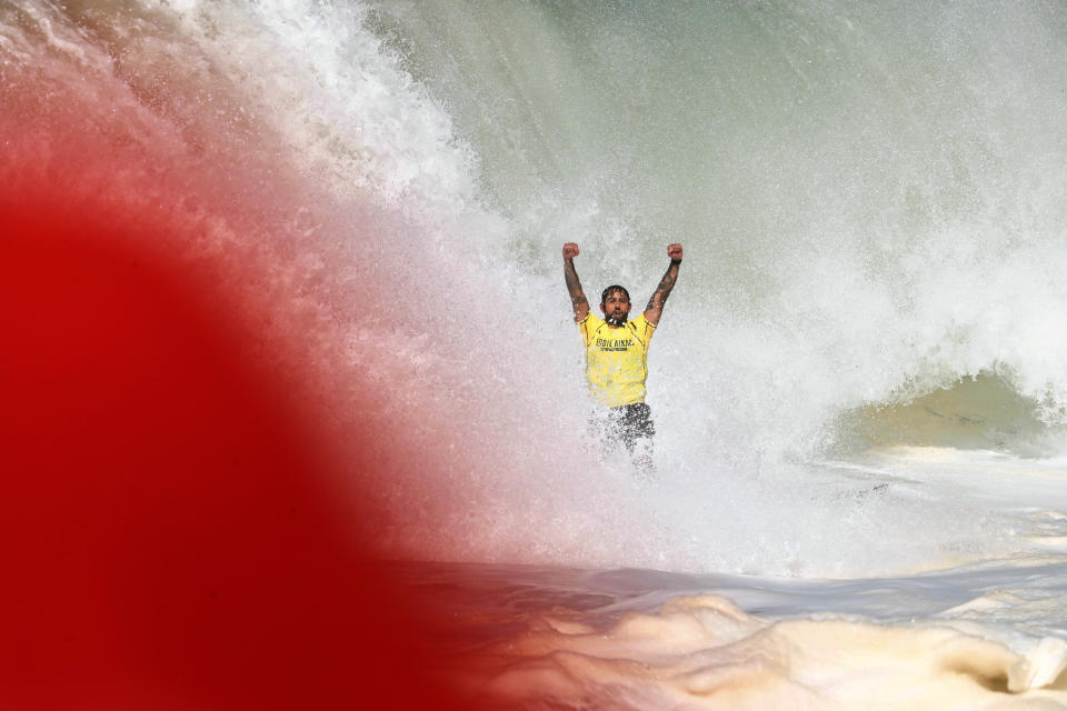 Billy Kemper throws up his arms up after completing his ride in Hawaii's Waimea Bay on Oahu’s North Shore during the The Eddie Aikau Big Wave Invitational surfing contest Sunday, Jan. 22, 2023. (Jamm Aquino/Honolulu Star-Advertiser via AP)