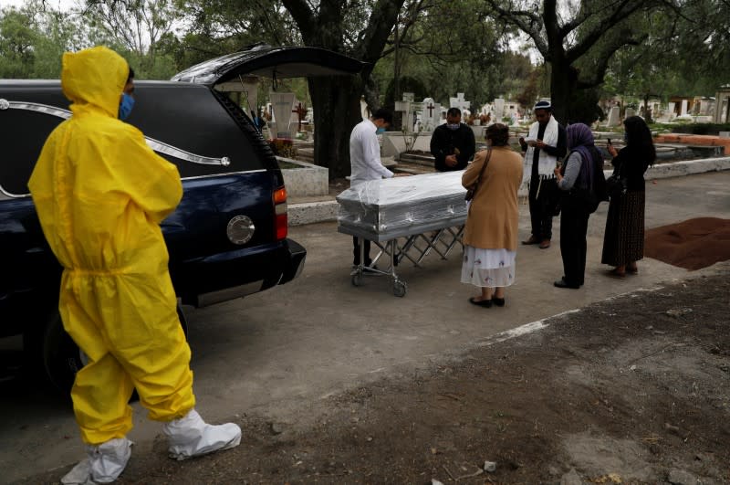 Family members surround the coffin containing the body of a woman who died of the coronavirus disease (COVID-19) at the San Rafael cemetery in Mexico City