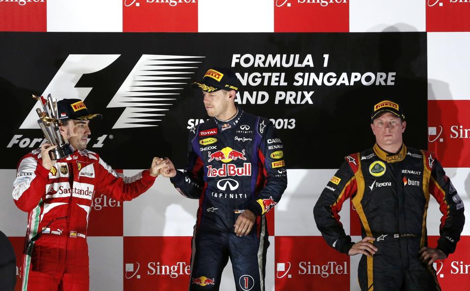 Red Bull Formula One driver Sebastian Vettel of Germany (C), Ferrari Formula One driver Fernando Alonso of Spain (L) and Lotus F1 Formula One driver Kimi Raikkonen of Finland (R) stand on the podium after the Singapore F1 Grand Prix at the Marina Bay street circuit in Singapore September 22, 2013. Vettel cruised to a third straight Singapore Grand Prix victory on Sunday and moved closer to a fourth consecutive Formula One world title with a dominant drive under the floodlights at the Marina Bay Street Circuit. REUTERS/Edgar Su (SINGAPORE - Tags: SPORT MOTORSPORT F1)