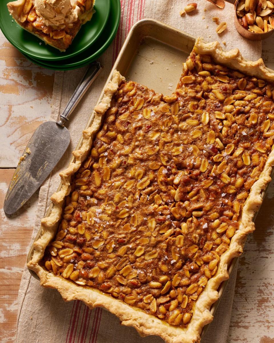 peanut salted caramel slab pie in a matte gold rectangle pan with a pie server and a slice of pie on a green plate