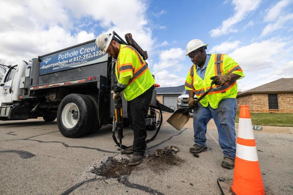 Pothole crew members Michael Cruz, left, and Vernon Sawyer work together to fill a pothole in the street at a neighborhood in Fort Worth on Thursday, Dec. 7, 2023.