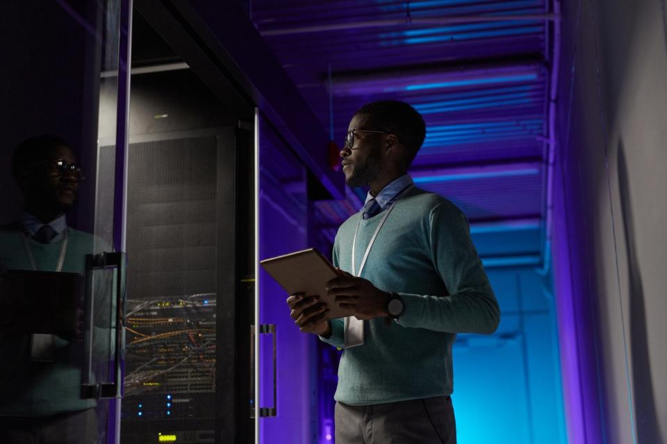 A person inside of a data center checking on server racks.