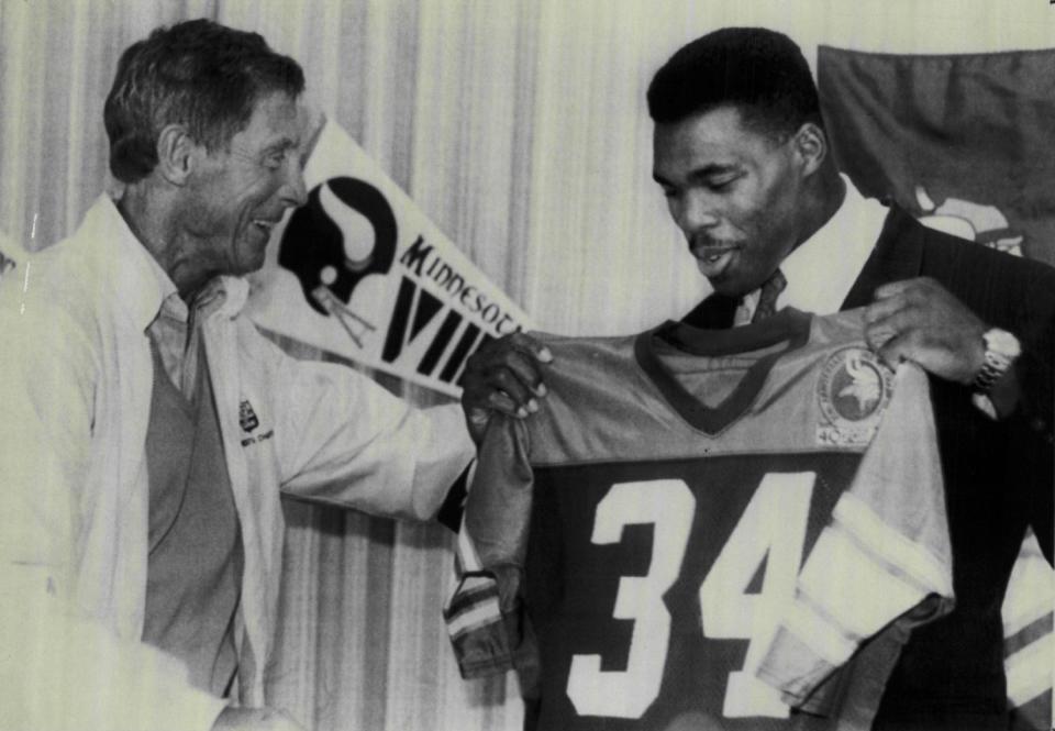 Herschel Walker holds up his No. 34 Vikings jersey during a 1989 press conference after he was traded by the Cowboys. (Sporting News via Getty Images)