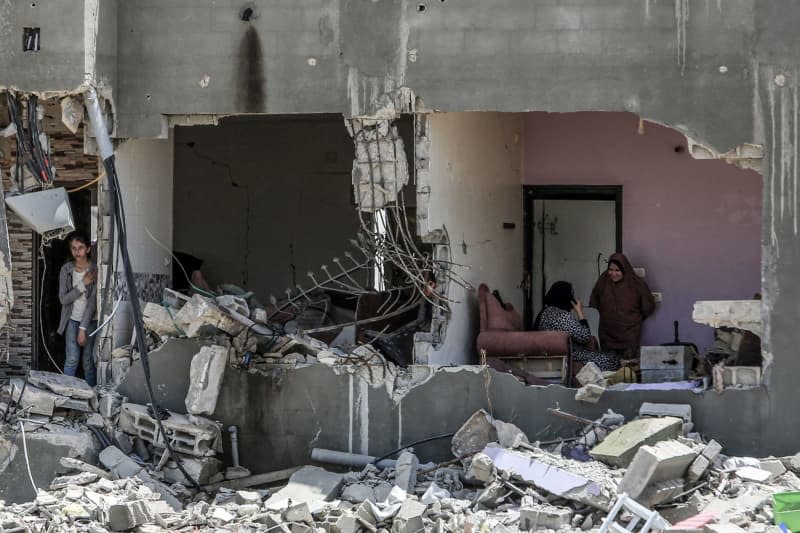 Palestinians sit inside a destroyed house caused by the Israeli army in the Al-Qarara neighbourhood. Abed Rahim Khatib/dpa