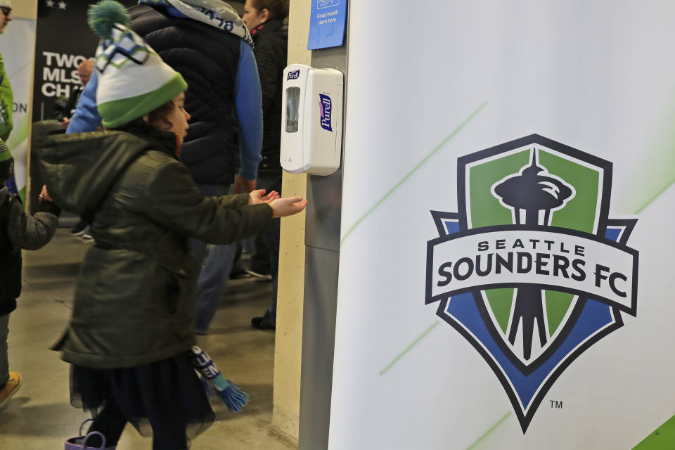 A young fan makes use of a hand-sanitizing station at CenturyLink Field prior to an MLS soccer match between the Seattle Sounders and the Chicago Fire, Sunday, March 1, 2020, in Seattle. Major North American professional sports leagues are talking to health officials and informing teams about the coronavirus outbreak. (AP Photo/Ted S. Warren)