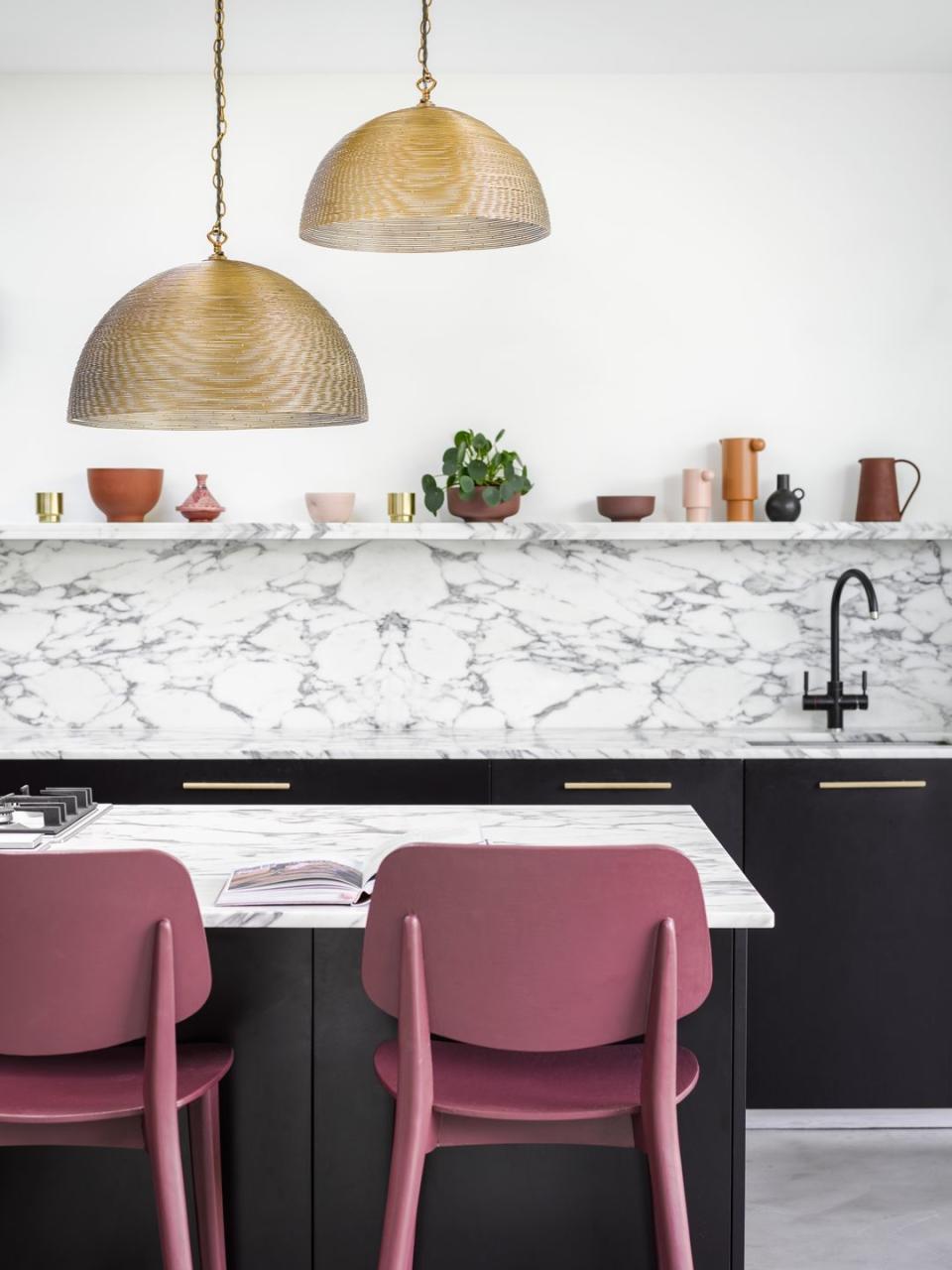 kitchen island with gold light and pink chairs