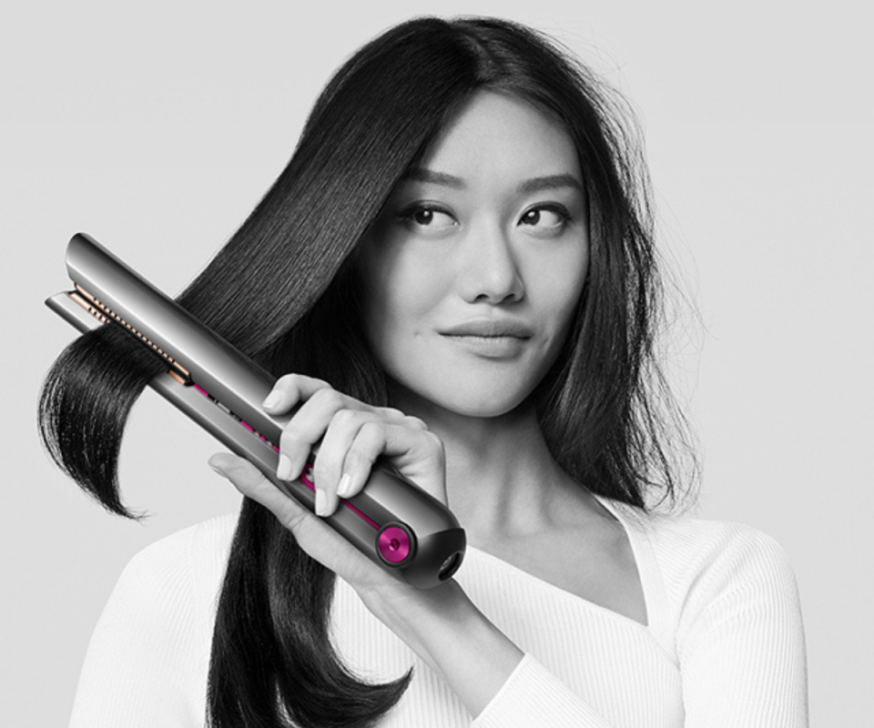 Woman using the Corrale straightener from Dyson