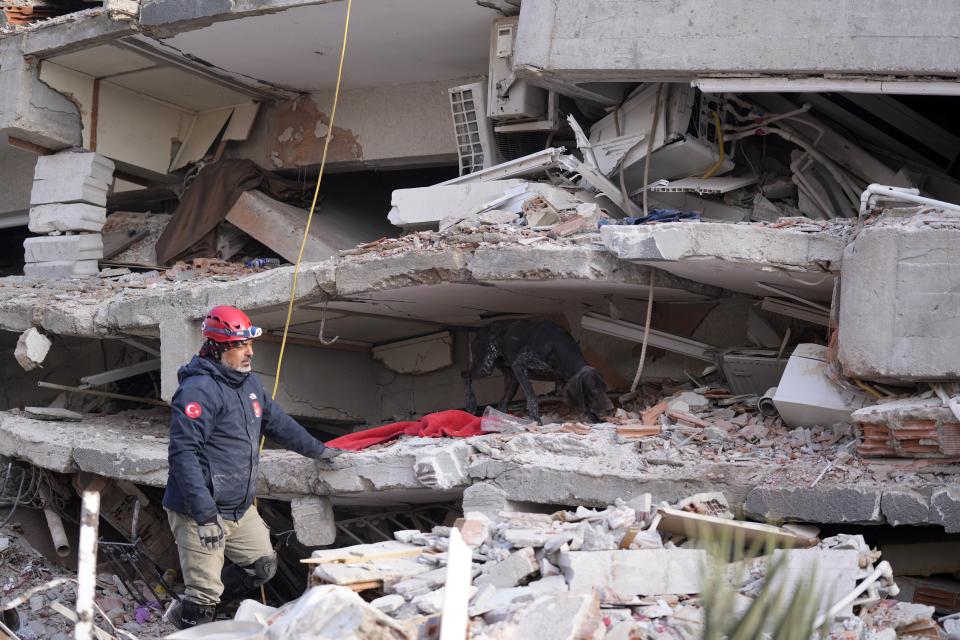 A rescuer with a sniffer dog searches in a destroyed building in Antakya, southeastern Turkey, Friday, Feb. 10, 2023. Rescuers pulled several earthquake survivors from the shattered remnants of buildings Friday, including some who lasted more than 100 hours trapped under crushed concrete after the disaster slammed Turkey and Syria. (AP Photo/Hussein Malla)