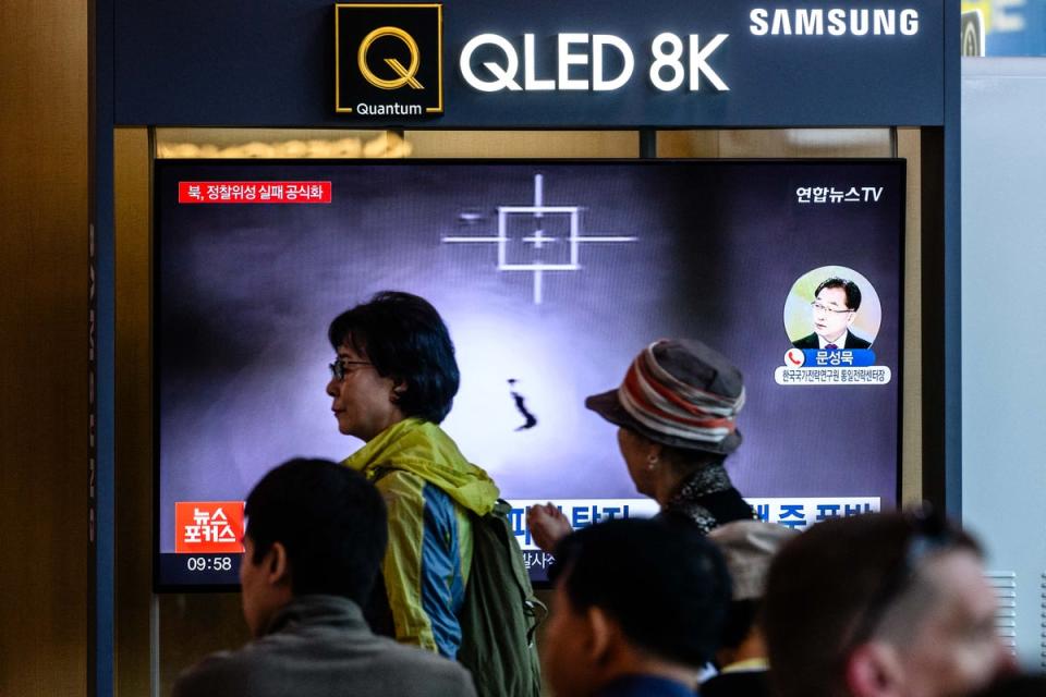 People walk past a TV showing the launch at a train station in Seoul (AFP via Getty)