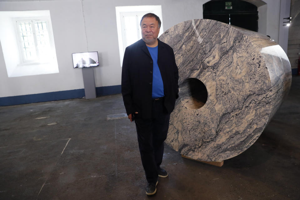 Dissident Chinese artist Ai Weiwei poses by one of his latest works, a giant toilet paper roll in marble, during a press preview of his new exhibition "Rapture" in Lisbon, Thursday, June 3, 2021. The world-renowned artist is putting on the biggest show of his career, and he is doing it in a place he's fallen in love with: Portugal. (AP Photo/Armando Franca)