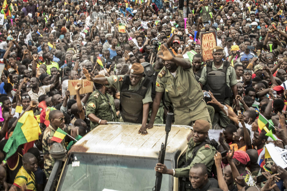 An unidentified representative of the junta waves from a military vehicle as Malians supporting the recent overthrow of President Ibrahim Boubacar Keita gather to celebrate in the capital Bamako, Mali Friday, Aug. 21, 2020. Hundreds marched in the streets of Mali's capital Friday to celebrate the overthrow of Keita, as the West African country's longtime political opposition backed the military's junta plan to eventually hand over power to a civilian transitional government. (AP Photo)