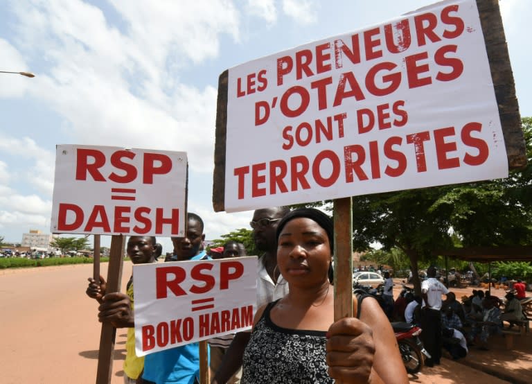 A protester holds a sign reading "Hostage takers are terrorists" and "Regiment of Presidential Security (RSP) = Daesh and Boko Haram" during a protest in Ouagadougou on September 23, 2015