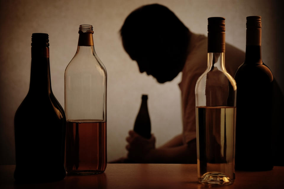 A person framed by bottles of alcoholic drinks.