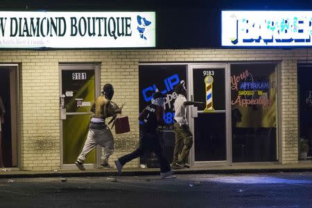 Masked individuals carry items out of a store, during on-going demonstrations to protest against the shooting of Michael Brown, in Ferguson, Missouri, August 16, 2014. REUTERS/Lucas Jackson