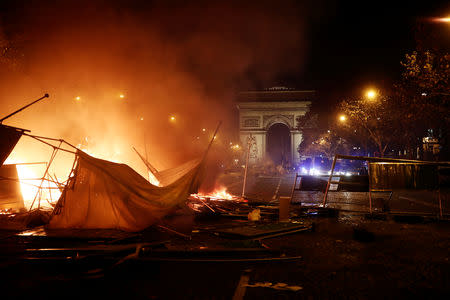 Police vans are seen behind a burning barricade during a "Yellow vest" protests against higher fuel prices, on the Champs-Elysees in Paris, France, November 24, 2018. REUTERS/Benoit Tessier