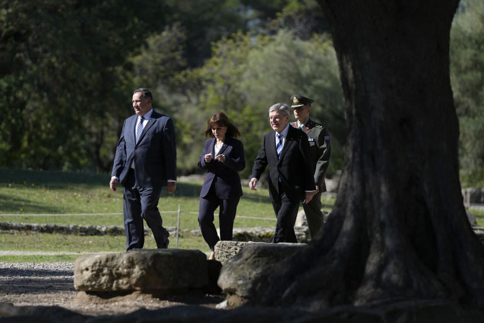 Hellenic Olympic Committee President Spyros Capralos, Greek President Katerina Sakellaropoulou and IOC President Thomas Bach, from left, arrive for the lighting of the Olympic flame at Ancient Olympia site, birthplace of the ancient Olympics in southwestern Greece, Monday, Oct. 18, 2021. The flame will be transported by torch relay to Beijing, China, which will host the Feb. 4-20, 2022 Winter Olympics. (AP Photo/Thanassis Stavrakis)