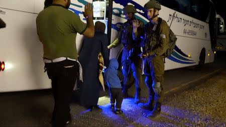 People walk past Israeli soldiers as they board a bus during the Syria Civil Defence, also known as the White Helmets, extraction from the Golan Heights, Israel in this still image taken from video, provided by the Israeli Army July 22, 2018. Israeli Army Handout via REUTERS