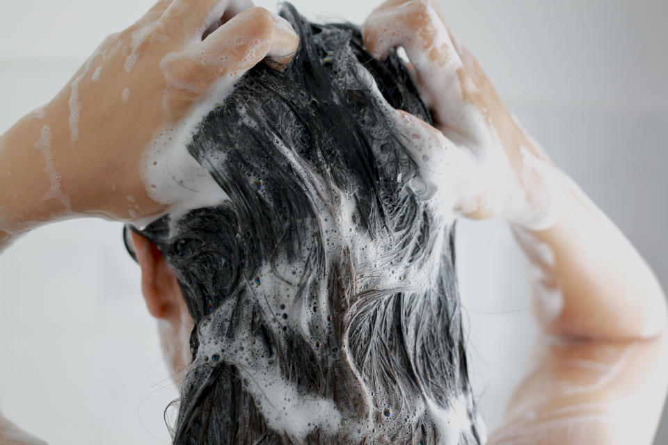 Woman is washing her hair with shampoo