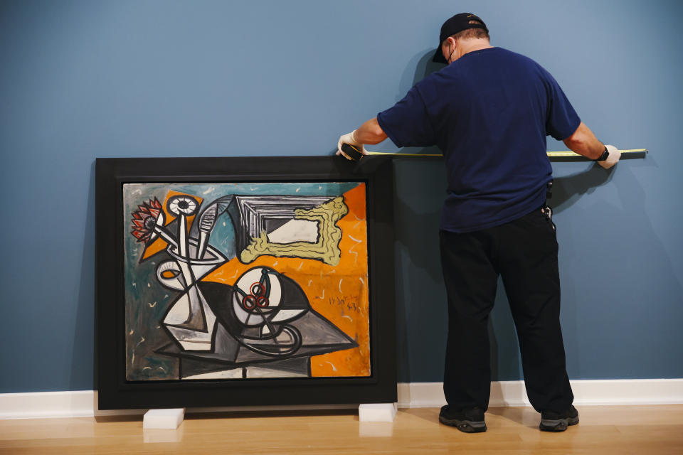 Art handler Terence McAllister prepares to hang a still life painting from 1943 by Pablo Picasso at the Bellagio Gallery of Fine Art Tuesday, Oct. 19, 2021 in Las Vegas. The artworks — nine are paintings and two are ceramic pieces — are part of MGM Resorts' collection and will be offered at auction Saturday. (Wade Vandervort/Las Vegas Sun via AP)