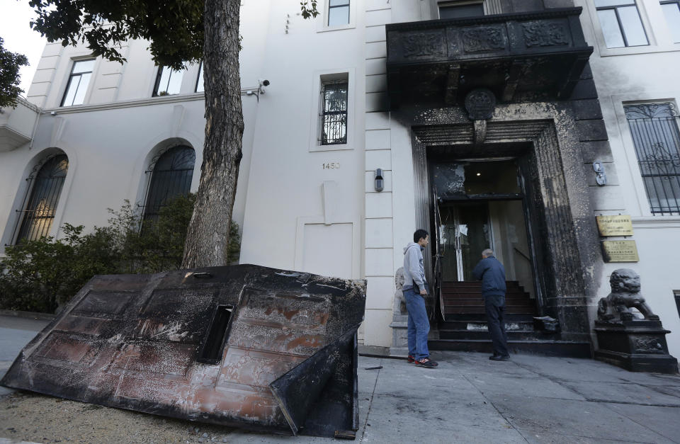 Two men look at the damage to the entrance of the Chinese Consulate in San Francisco on Thursday, Jan. 2, 2014. The consulate said in a notice on its website that a person came out of a van parked outside the compound Wednesday night with two buckets of gasoline, poured the fuel on the front of the consulate building and set it on fire. (AP Photo/Jeff Chiu)