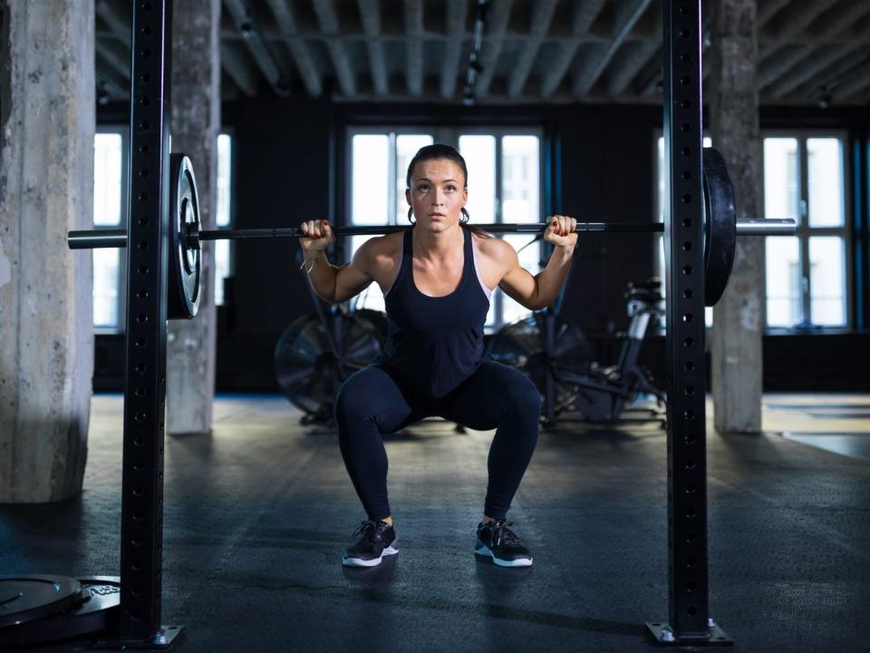 A woman performing a barbell back squat.