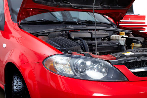 Car with open hood in auto repair shop.