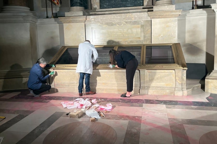 National Archives employees clean pink powder on the casement of the U.S. Constitution inside the National Archives Rotunda in Washington, Feb. 14, 2024. The National Archives building and galleries were evacuated after two protesters dumped powder on the protective casing around the U.S. Constitution. (William J. Bosanko/National Archives via AP)
