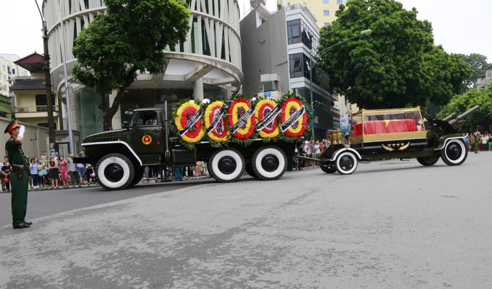 An army officer salutes as national flag-draped coffin of late President Tran Dai Quang on truck-drawn artillery carriage passes by in Hanoi, Vietnam, Thursday, Sept. 27, 2018. Thousands of people line streets in capital Hanoi to pay their last respects to the late president who died last week of viral illness. (AP Photo/Tran Van Minh)