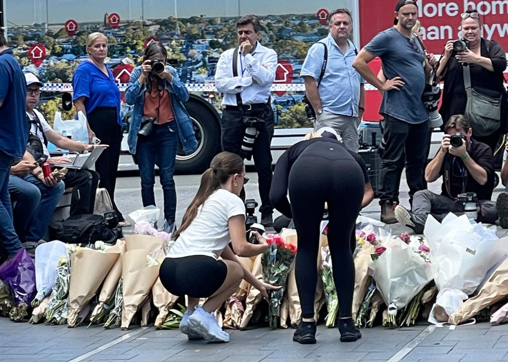 Two women add flowers to a floral tribute on Sunday. Source: Michael Dahlstrom