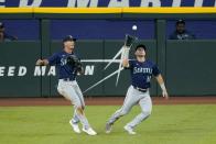 Seattle Mariners left fielder Dylan Moore watches as center fielder Jarred Kelenic, right, catches a fly ball hit by Texas Rangers' Jonah Heim during the second inning of a baseball game in Arlington, Texas, Friday, July 30, 2021. (AP Photo/Tony Gutierrez)