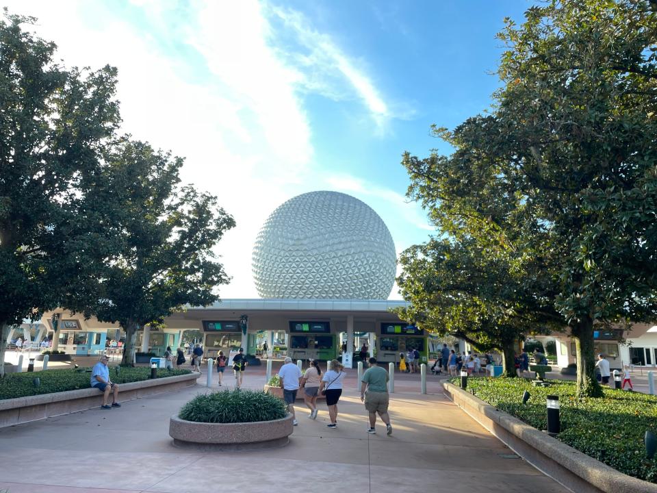 a few people walking toward epcot early in the morning when it first opens