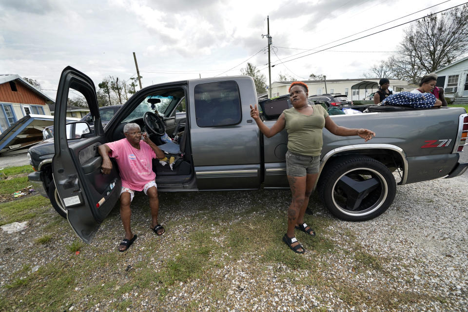 Loubertha Rideaux, left, sits on the door jamb of a truck in Lake Charles, La., as her daughter Patricia Mingo Lavergne reacts, after they returned form evacuation in the aftermath of Hurricane Laura, Sunday, Aug. 30, 2020. They evacuated and returned in the truck with eight adults and one child. (AP Photo/Gerald Herbert)