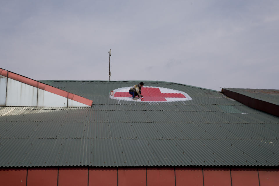 A Kashmiri worker paints the red and white medical emblem of cross on the roof of SMHS hospital as tensions escalate between India and Pakistan in Srinagar, Indian controlled Kashmir, Wednesday, Feb. 27, 2019. (AP Photo/ Dar Yasin)