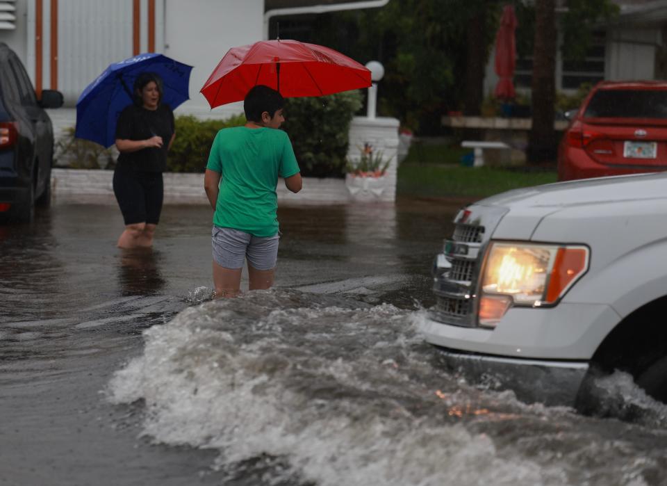 HOLLYWOOD, FLORIDA - JUNE 12: People walk through a flooded street on June 12, 2024, in Hollywood, Florida. As tropical moisture passes through the area, areas have become flooded due to the heavy rain. (Photo by Joe Raedle/Getty Images)