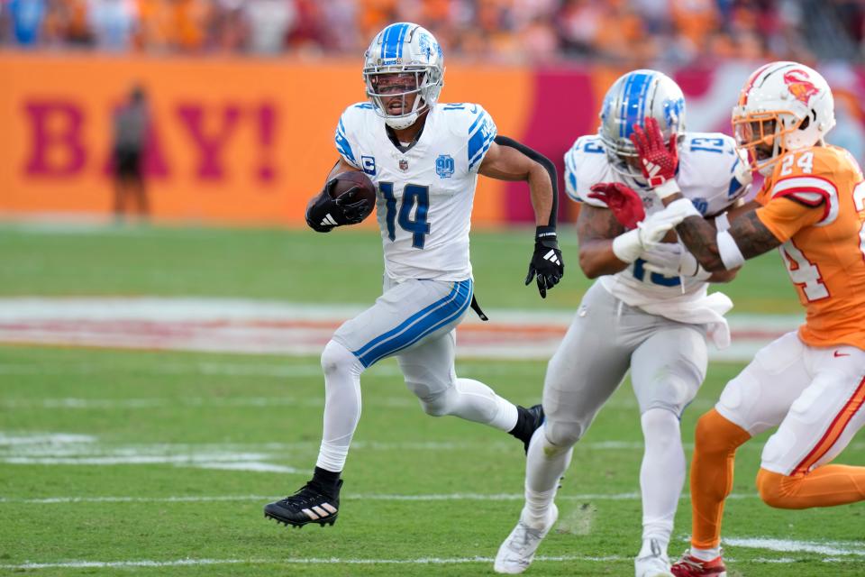 Detroit Lions wide receiver Amon-Ra St. Brown (14) scores on a 27-yard touchdown reception as running back Craig Reynolds (13) blocks Tampa Bay Buccaneers cornerback Carlton Davis III (24) during the first half at Raymond James Stadium in Tampa, Florida, on Sunday, Oct. 15, 2023.