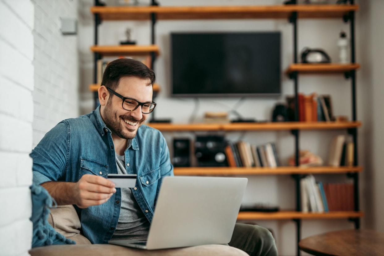 Handsome man with laptop and credit card at home, portrait.