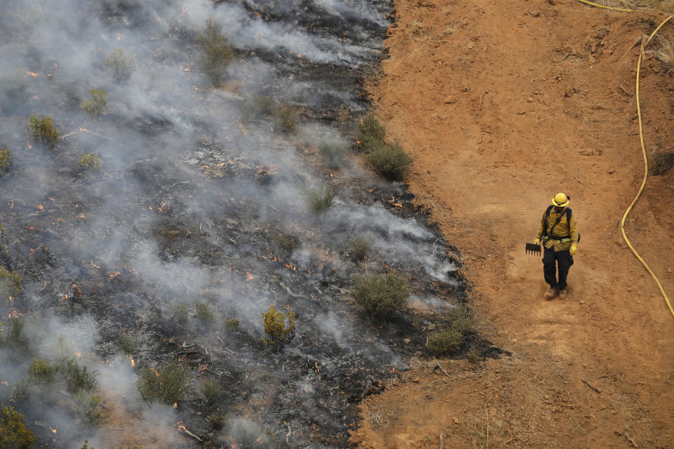 A firefighter walks along a containment line while battling a wildfire Saturday, July 28, 2018, in Redding, California.