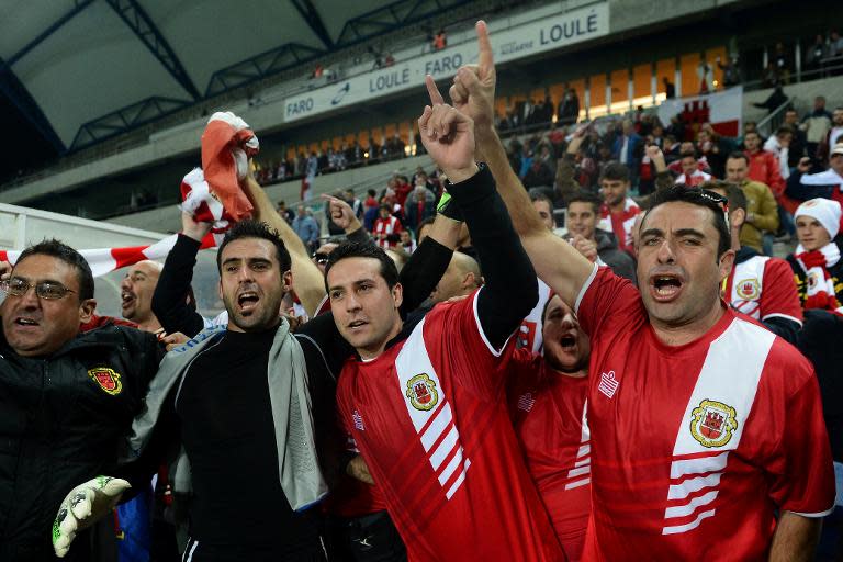 Gibraltar's goalkeeper Jordan Perez (2ndL) celebrates with supporters at the end of the World Cup 2014 friendly football match against Slovakia at Algarve stadium in Faro on November 19, 2013