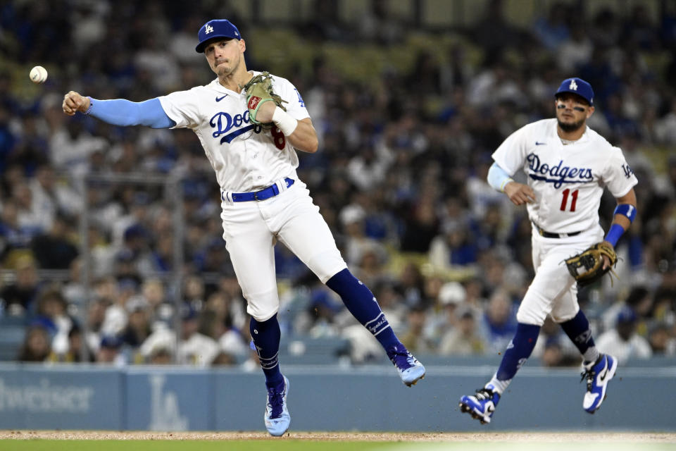 Los Angeles Dodgers third baseman Kiké Hernández, left, throws to first to put out San Francisco Giants' Mitch Haniger on a ground ball during the second inning of a baseball game in Los Angeles, Friday, Sept. 22, 2023. Dodgers shortstop Miguel Rojas (11) looks on. (AP Photo/Alex Gallardo)