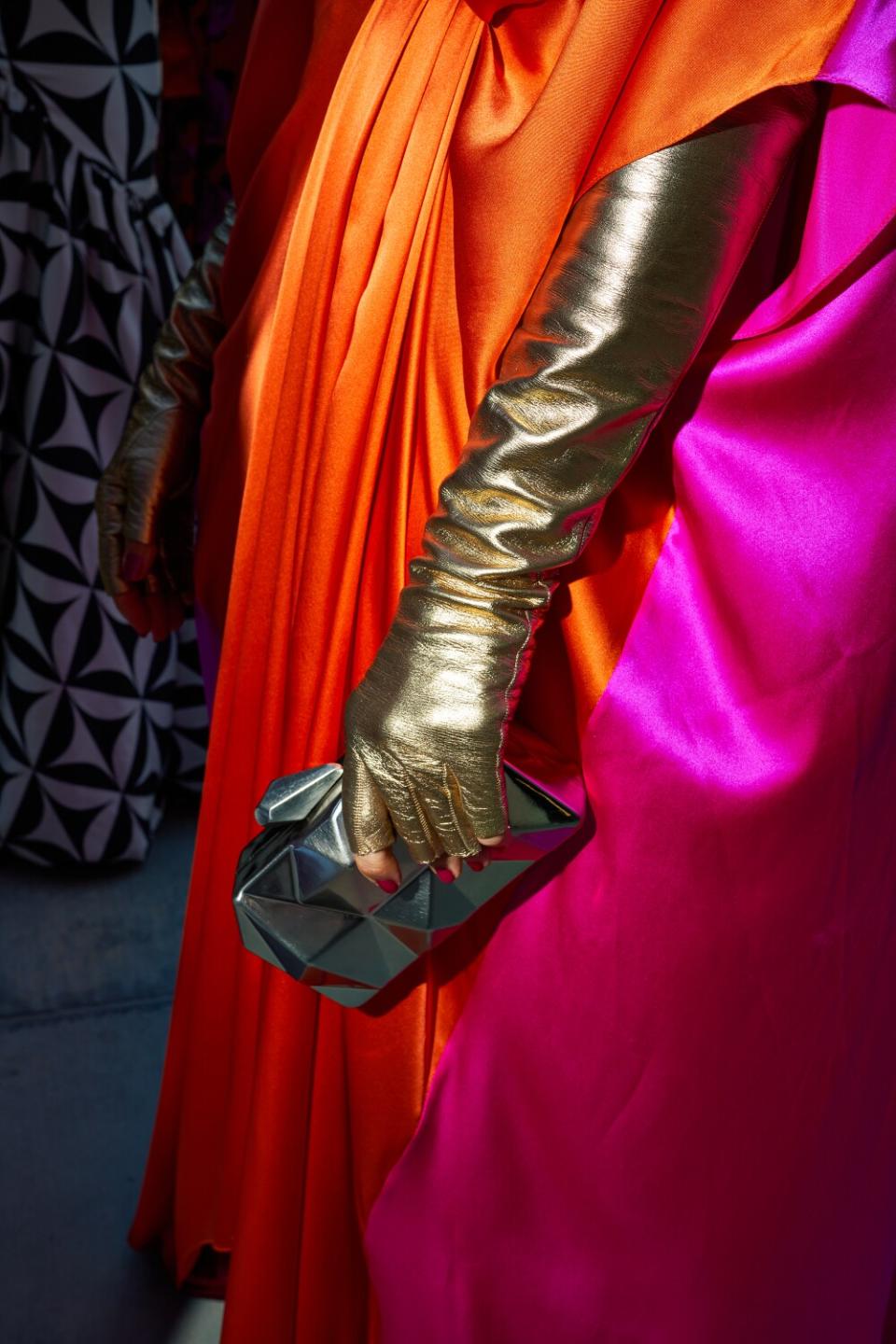 A woman in a gold glove clutches a bag.