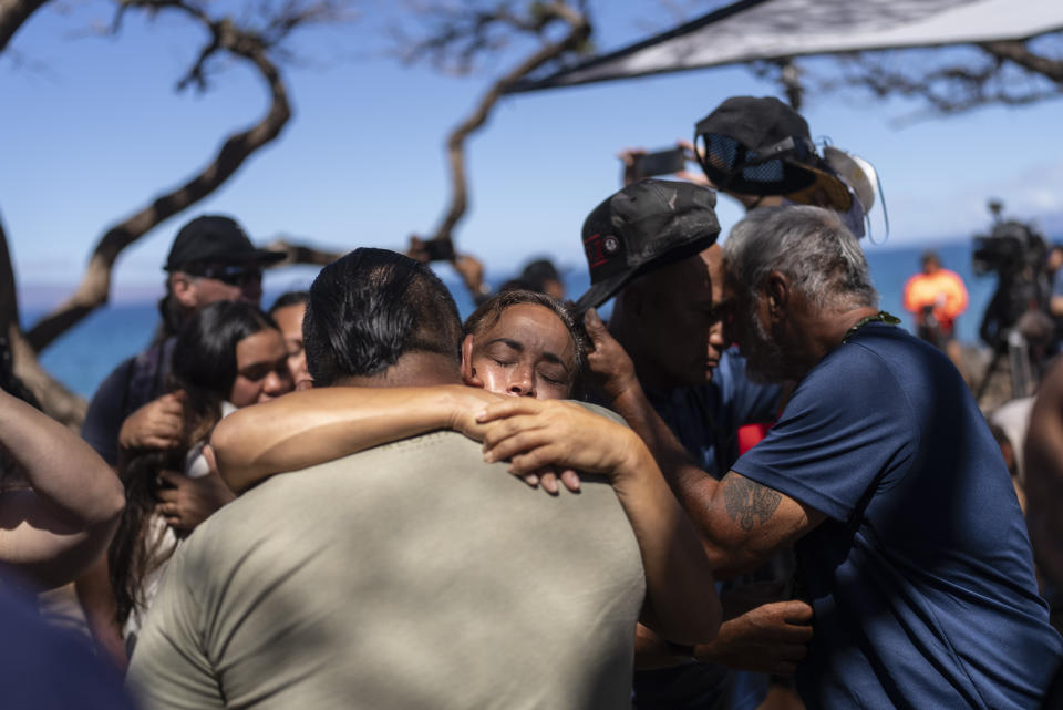 Lahaina, Hawaii, residents, who are affected by a deadly wildfire that devastated the community, hug one another after a news conference in Lahaina, Hawaii, Friday, Aug. 18, 2023. (AP Photo/Jae C. Hong)