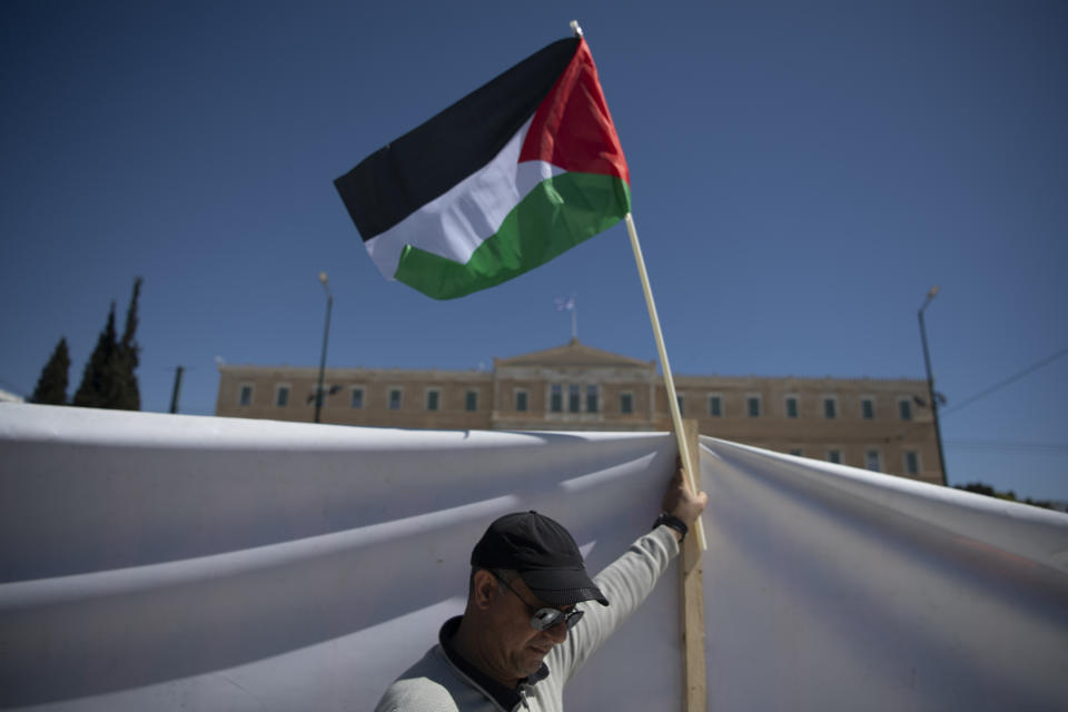 A man holds a Palestinian flag during a protest rally at Syntagma Square, central Athens, Greece, Saturday, March 30, 2024. Palestinians living in Greece rallied in front of the Parliament to protest Israel's military operations in the Gaza Strip. (AP Photo/Michael Varaklas)
