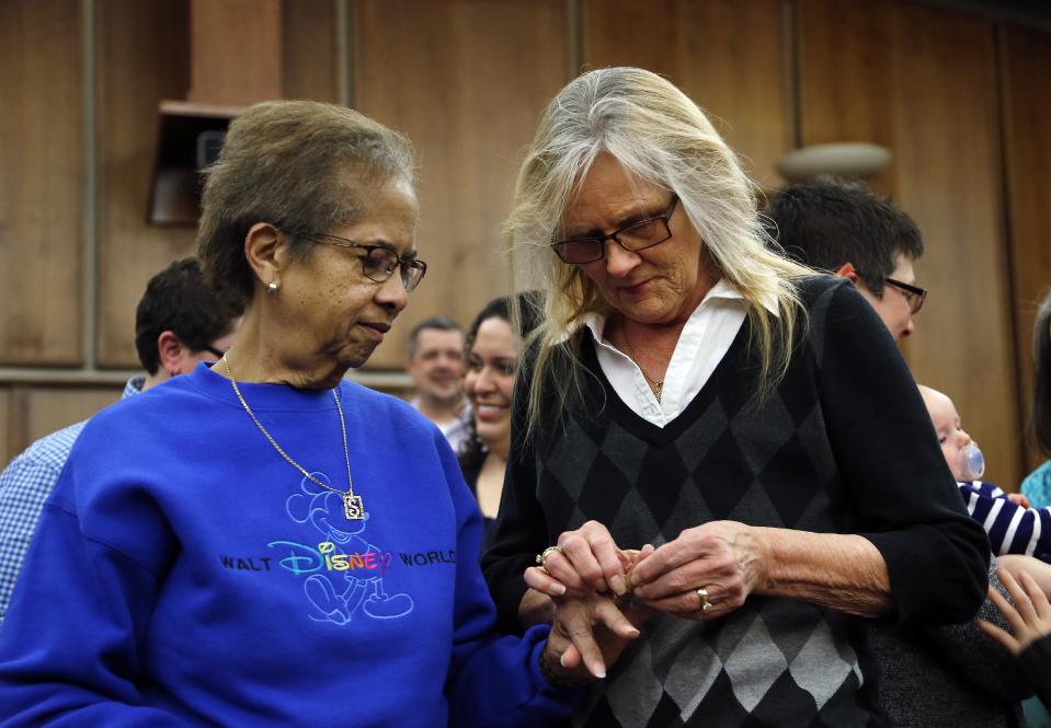 FILE - In this March 22, 2014 file photo Pennye Mattson, right, places a wedding ring on Sherrie Tyler, left, while being married in a group by the Oakland County Clerk in Pontiac, Mich., after a federal judge has struck down Michigan's ban on gay marriage. Attorney General Eric Holder on Friday, March 28, 2014 extended federal recognition to the marriages of about 300 same-sex couples that took place in Michigan before a federal appeals court put those unions on hold. (AP Photo/Paul Sancya, File)