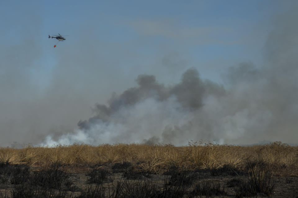 Un helicóptero de extinción de incendios sobrevuela un incendio forestal cerca de Villa Constitución, Argentina, el jueves 15 de septiembre de 2022. (AP Foto/Víctor R. Caivano)
