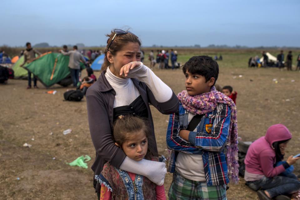 A migrant from Syria cries as she stands with her children on a field after crossing into Hungary from the border with Serbia near the village of Roszke, September 5, 2015. Austria and Germany threw open their borders to thousands of exhausted migrants on Saturday, bussed to the Hungarian border by a right-wing government that had tried to stop them but was overwhelmed by the sheer numbers reaching Europe's frontiers. Left to walk the last yards into Austria, rain-soaked migrants, many of them refugees from Syria's civil war, were whisked by train and shuttle bus to Vienna, where many said they were resolved to continue on to Germany. REUTERS/Marko Djurica