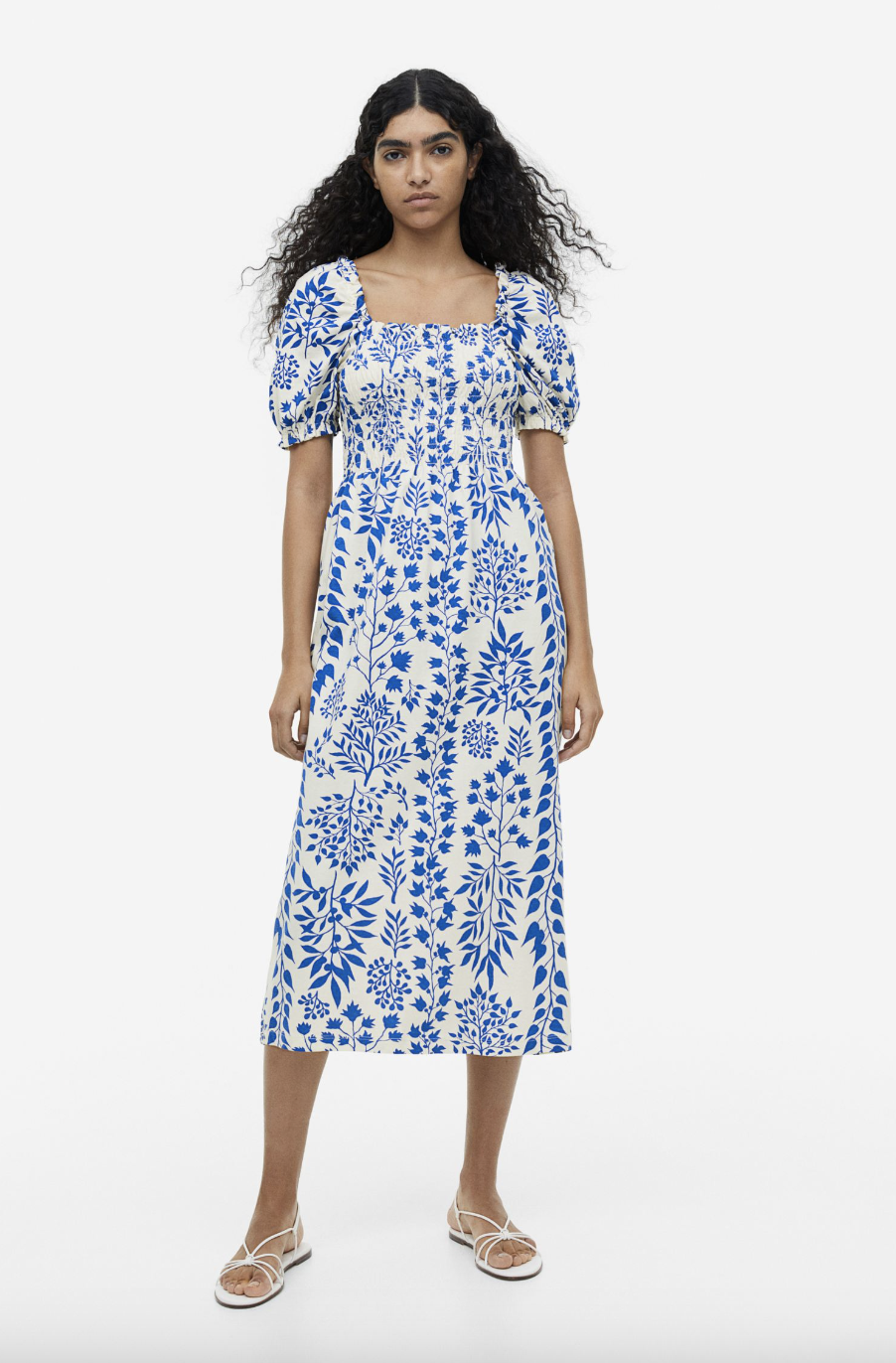 model with long black curly hair wearing floral blue and white printed Smocked Jersey Dress (photo via H&M)